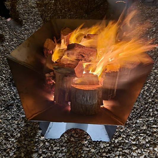 Fire burning in a metal fire pit on a gravel surface