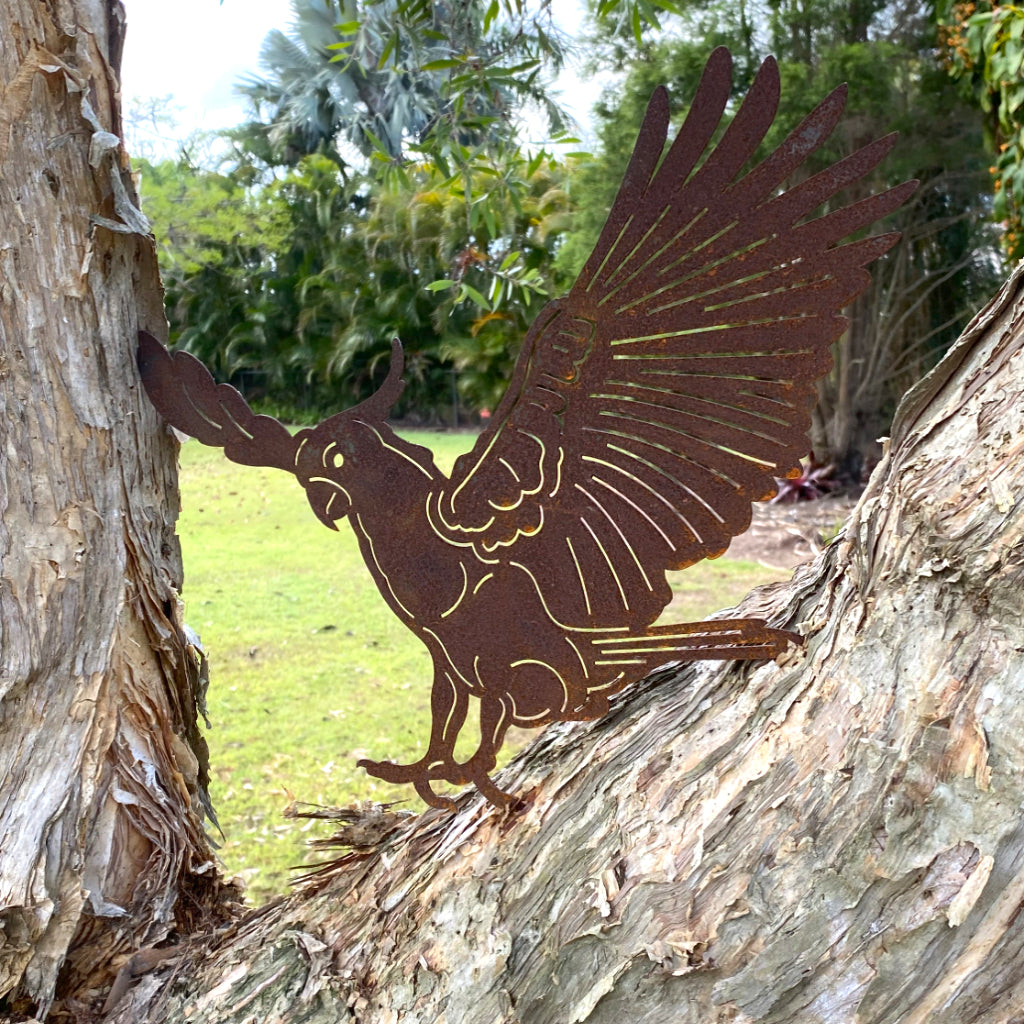 Metal cockatoo bird sculpture on a tree trunk with a natural background