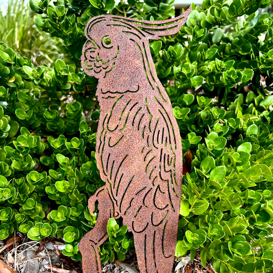 Metallic cockatoo bird sculpture against a green bush background