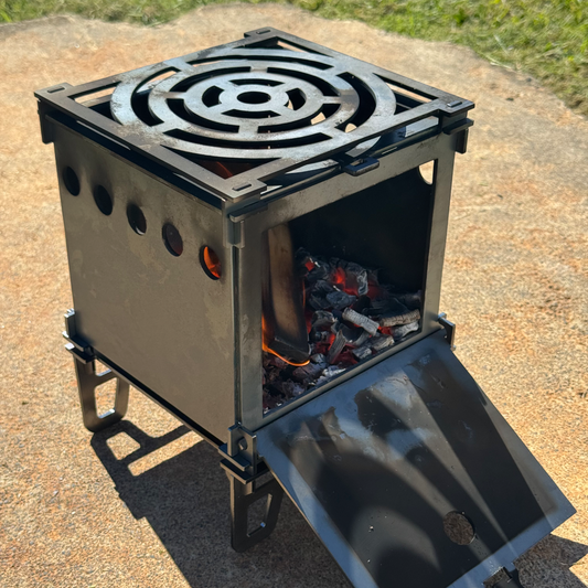 Portable metal stove with fire burning inside on a concrete surface